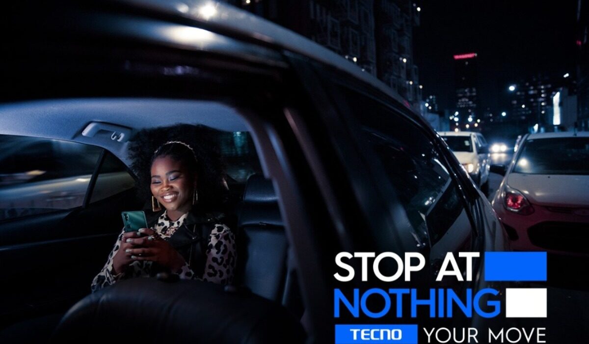 Stop At Nothing - A black lady holding a techno phone in a car and smiling.